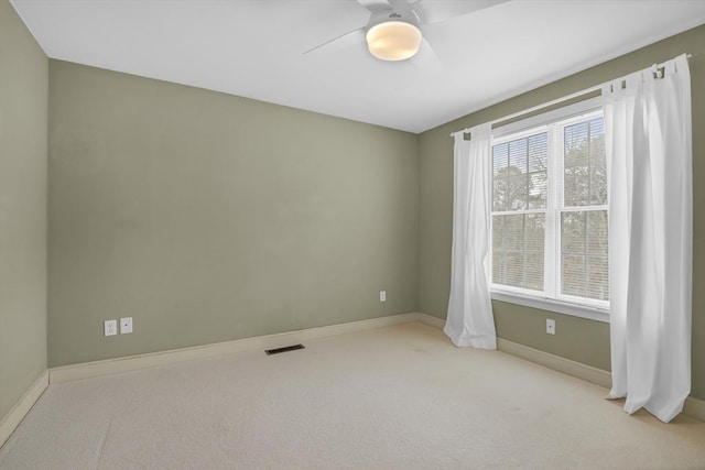 empty room featuring carpet floors, visible vents, ceiling fan, and baseboards