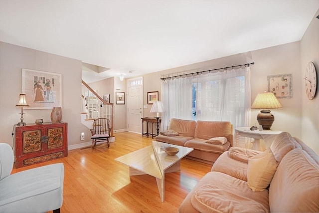 living room featuring light wood-style floors, stairway, and baseboards