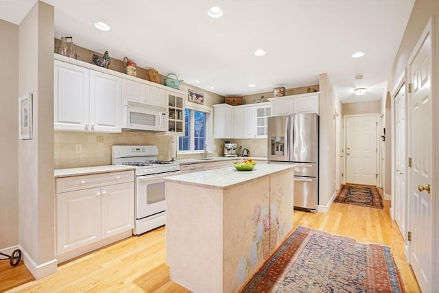 kitchen featuring glass insert cabinets, light wood-type flooring, white appliances, and white cabinets