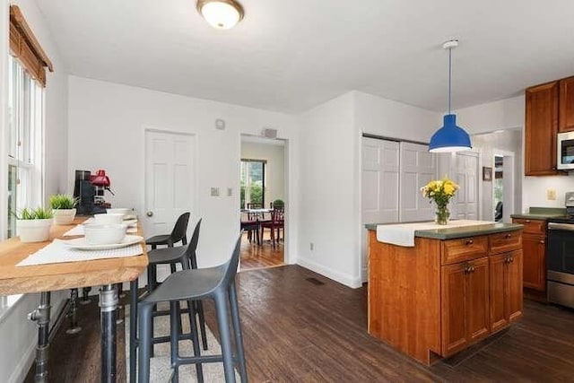 6 Francis Ave, Wakefield, MA 01880 - kitchen featuring appliances with stainless steel finishes, dark wood-type flooring, a center island, brown cabinetry, and baseboards