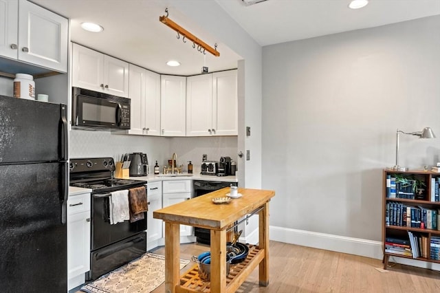 762 Tremont St Unit 5, Boston, MA 02118 - kitchen with black appliances, light countertops, white cabinets, light wood finished floors, and recessed lighting
