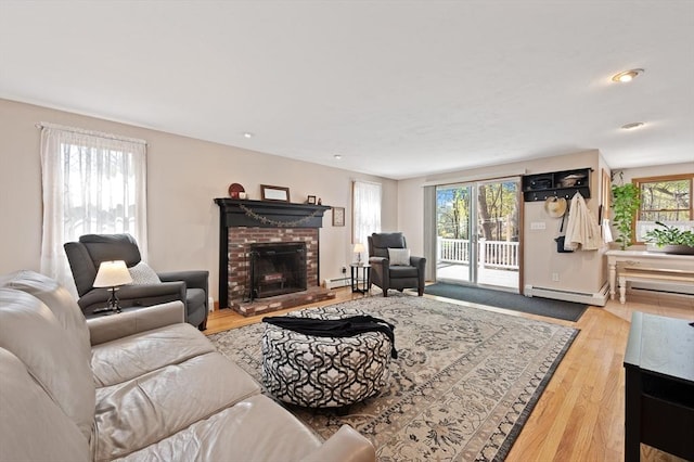 living room featuring a brick fireplace, wood finished floors, a baseboard radiator, baseboard heating, and baseboards
