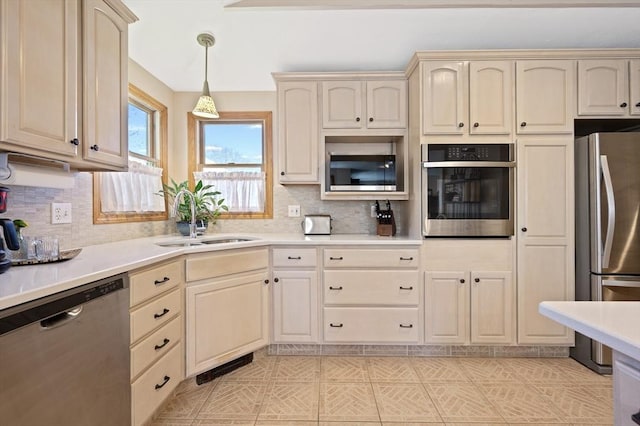 kitchen with stainless steel appliances, a sink, cream cabinetry, and light countertops