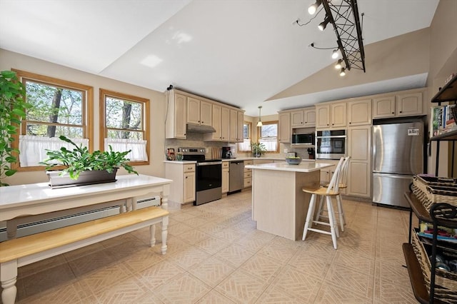 kitchen featuring appliances with stainless steel finishes, vaulted ceiling, light countertops, baseboard heating, and a kitchen bar