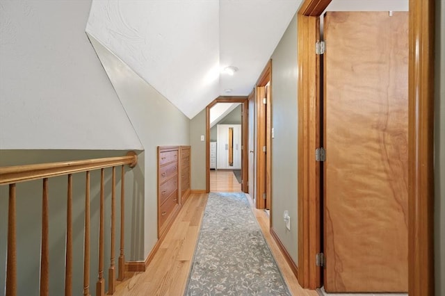 hallway featuring light wood-type flooring and vaulted ceiling