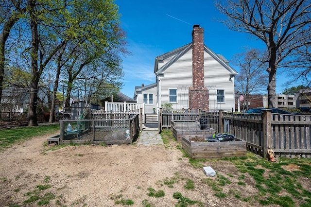 rear view of property with a garden, a chimney, and fence