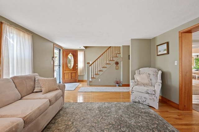 living room featuring wood finished floors, baseboards, and stairway