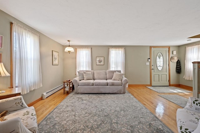 living room featuring a baseboard heating unit, healthy amount of natural light, and wood finished floors