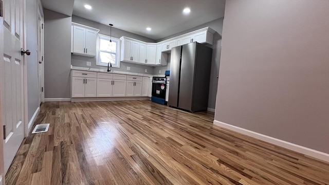 kitchen with white cabinetry, hardwood / wood-style floors, stainless steel appliances, decorative light fixtures, and sink