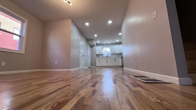 unfurnished living room featuring sink, a wealth of natural light, and hardwood / wood-style floors