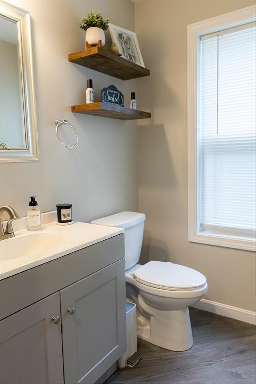 82 Davenport St, Springfield, MA 01119 - half bathroom featuring toilet, vanity, baseboards, wood finished floors, and plenty of natural light