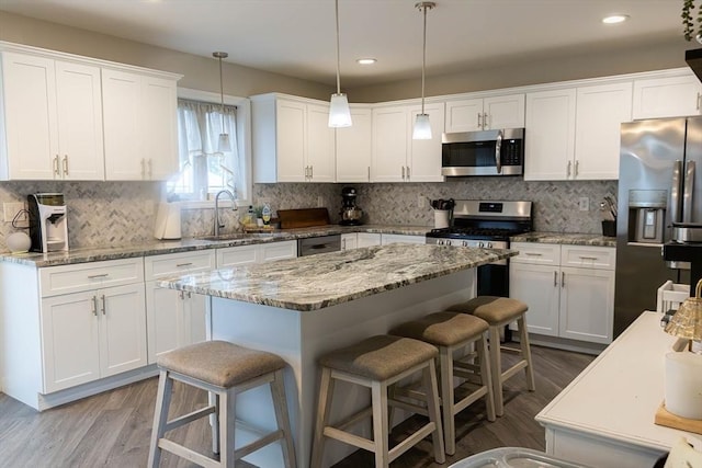 82 Davenport St, Springfield, MA 01119 - kitchen with appliances with stainless steel finishes, a sink, a kitchen bar, white cabinets, and a center island
