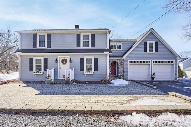 traditional-style home featuring aphalt driveway, a chimney, and a garage