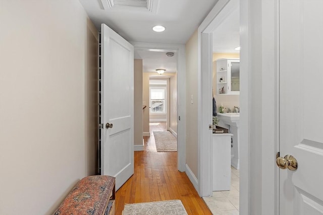 hallway with baseboards, visible vents, and light wood finished floors