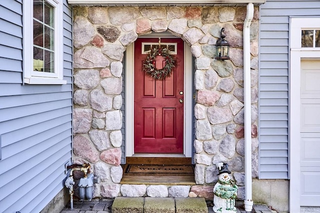 property entrance featuring a garage and stone siding