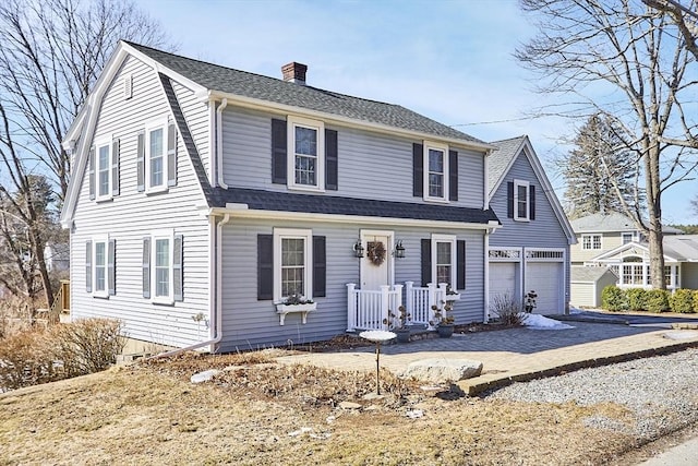 view of front of house with a garage, roof with shingles, a chimney, and a gambrel roof