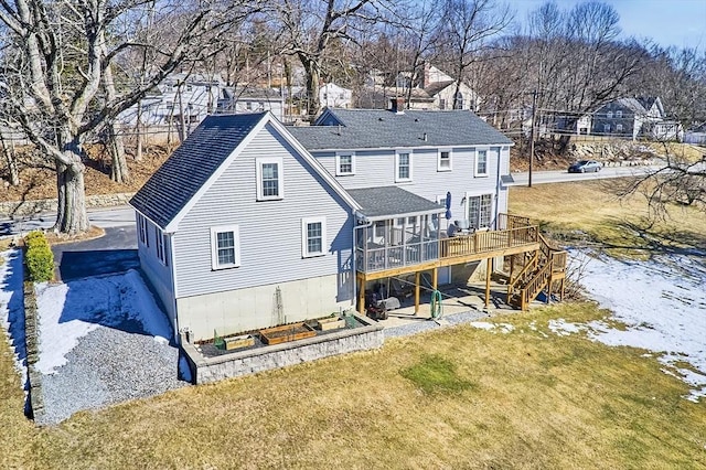 back of house featuring a sunroom, a residential view, stairway, a deck, and a yard