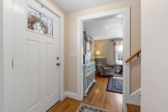 entryway with light wood-style flooring, stairs, and baseboards