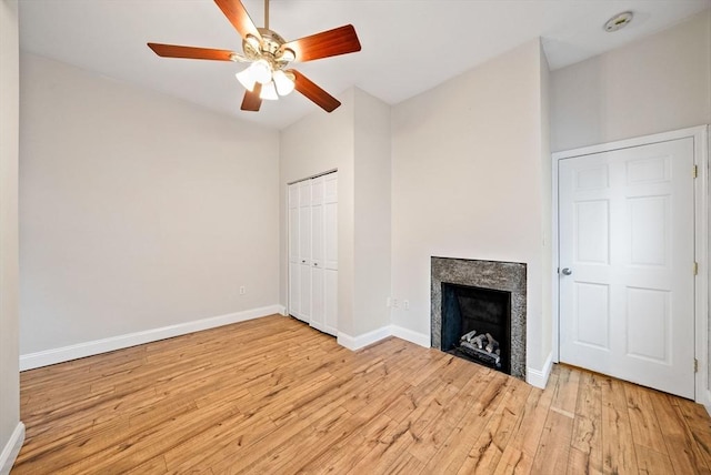 unfurnished living room featuring wood finished floors, baseboards, a ceiling fan, and a fireplace