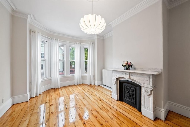 unfurnished living room with baseboards, light wood-style flooring, a fireplace, crown molding, and a chandelier