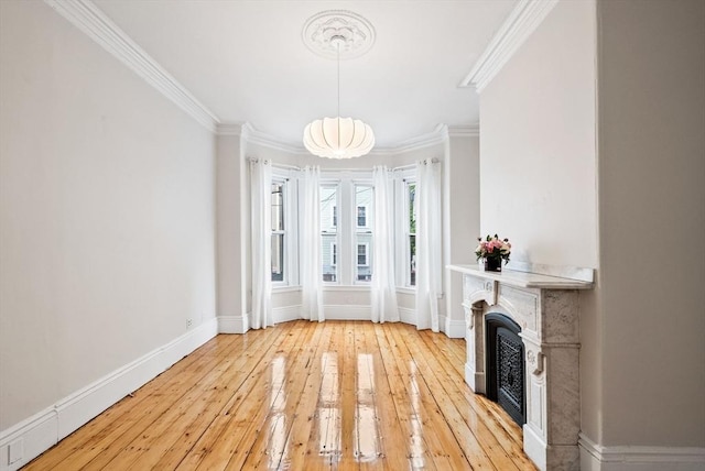 unfurnished living room featuring ornamental molding, light wood-style flooring, baseboards, and a fireplace