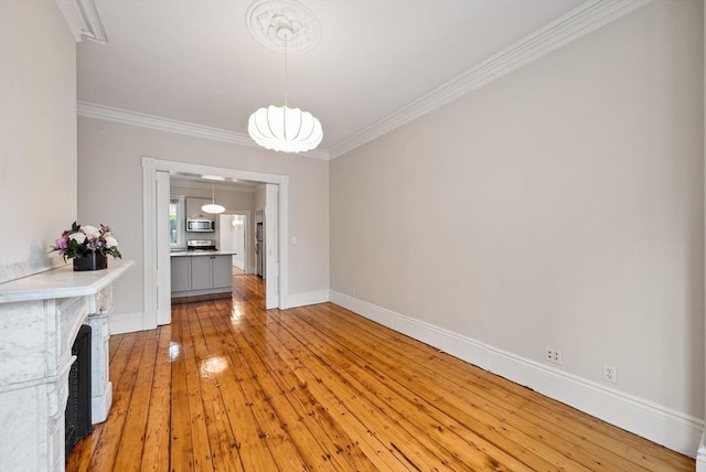 unfurnished dining area with crown molding, light wood finished floors, and baseboards