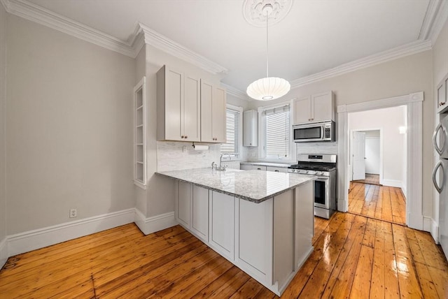 kitchen featuring stainless steel appliances, a peninsula, light wood-style floors, crown molding, and tasteful backsplash