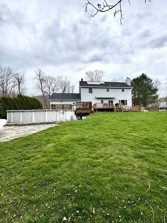 16 E Rd, Adams, MA 01220 - rear view of property with a chimney, an outdoor pool, roof mounted solar panels, a yard, and a wooden deck
