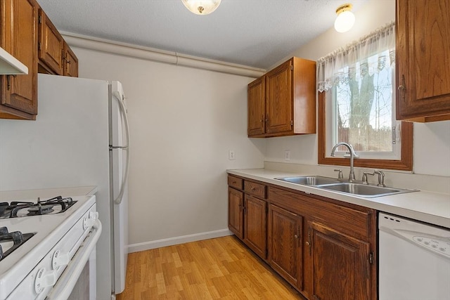 kitchen featuring sink, white appliances, light hardwood / wood-style floors, and extractor fan