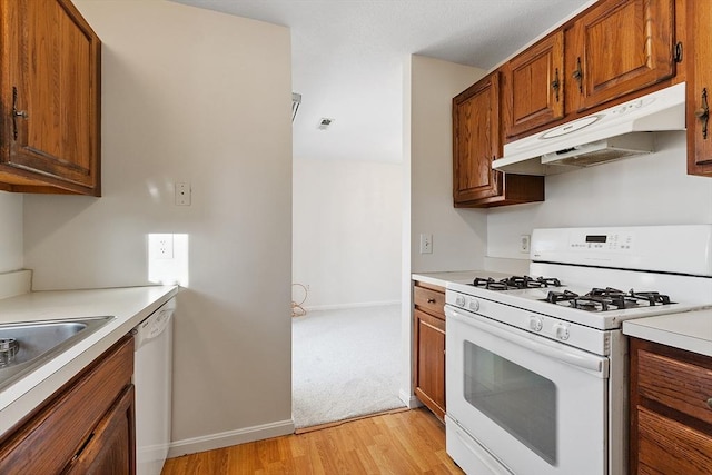 kitchen featuring white appliances, sink, and light hardwood / wood-style flooring