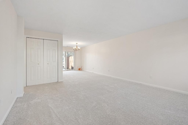 unfurnished bedroom featuring light colored carpet, a chandelier, and a closet