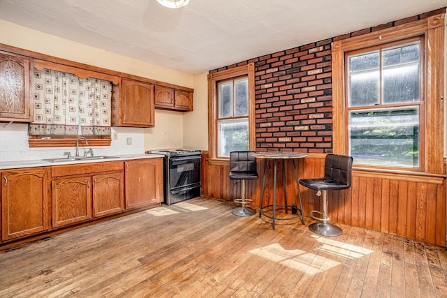 15 Green St, Gardner, MA 01440 - kitchen with black range oven, brown cabinets, light wood-type flooring, plenty of natural light, and wooden walls