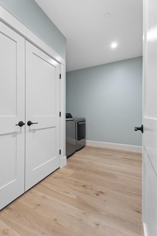 hallway with washing machine and clothes dryer and light hardwood / wood-style floors