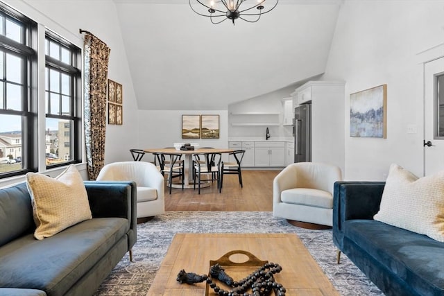 living room featuring an inviting chandelier, high vaulted ceiling, and light wood-type flooring