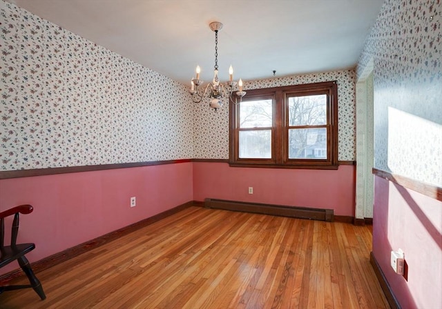 unfurnished room featuring wallpapered walls, baseboards, a baseboard heating unit, and wood finished floors