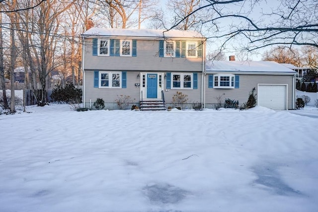 colonial home featuring entry steps, an attached garage, and a chimney