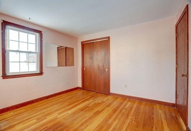 unfurnished bedroom with light wood-style floors, a closet, and baseboards