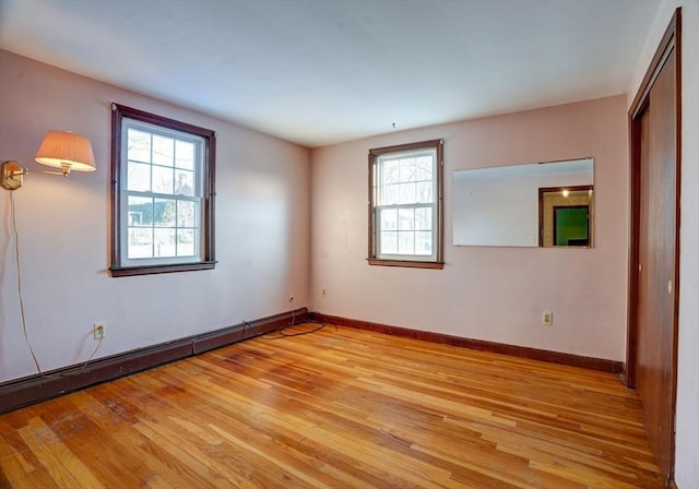 spare room with light wood finished floors, a baseboard radiator, and baseboards