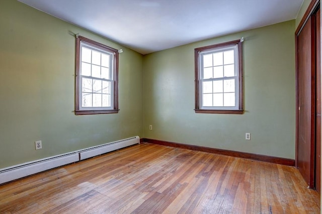 unfurnished room with light wood-style floors, baseboards, and a baseboard heating unit