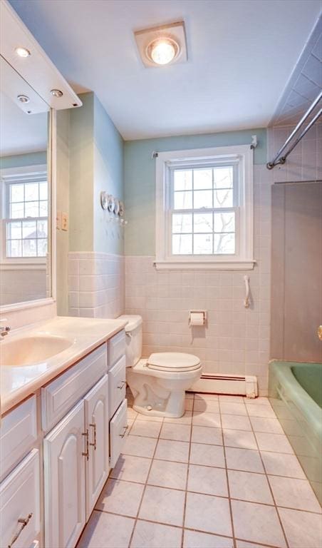 bathroom featuring toilet, a baseboard heating unit, tile walls, vanity, and tile patterned floors