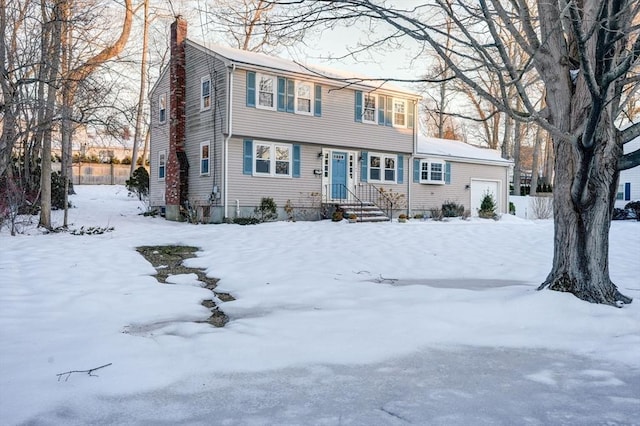 colonial-style house featuring a garage and a chimney