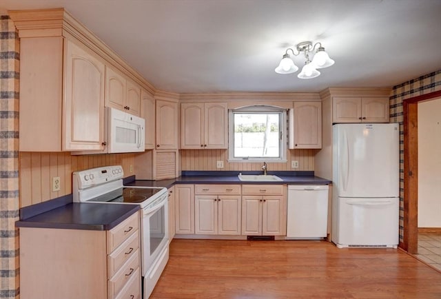 kitchen with a chandelier, white appliances, a sink, light wood-style floors, and dark countertops