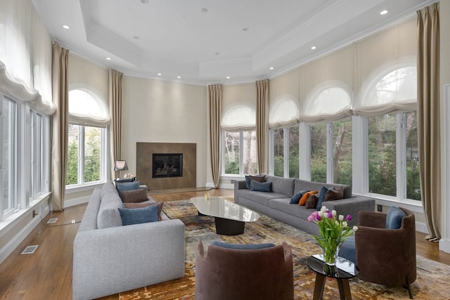 living room with ornamental molding, wood-type flooring, and a tray ceiling