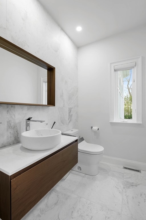 bathroom featuring vanity, toilet, and tile walls