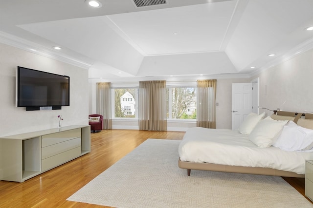 bedroom with crown molding, a tray ceiling, and light hardwood / wood-style flooring