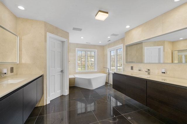 bathroom with vanity, a tub to relax in, and tile walls