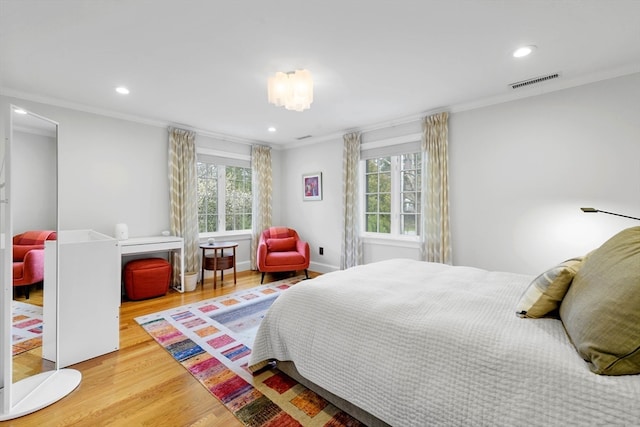 bedroom with ornamental molding, multiple windows, and hardwood / wood-style floors