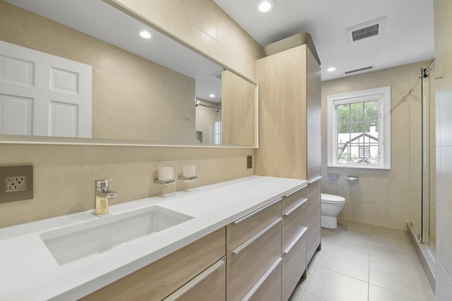 bathroom featuring toilet, tile patterned flooring, vanity, tile walls, and walk in shower