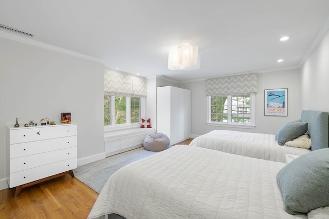 bedroom featuring light hardwood / wood-style floors, crown molding, and multiple windows