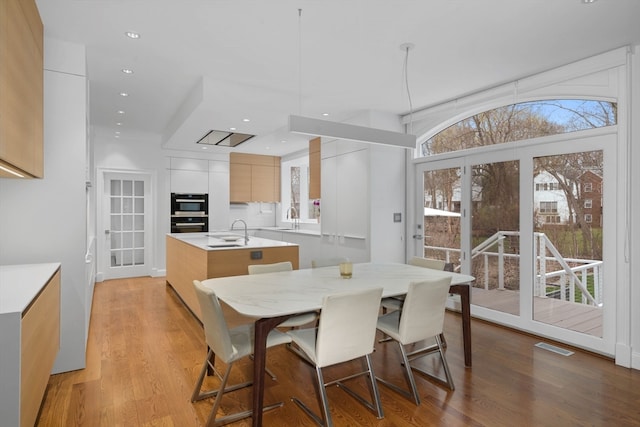 dining space featuring light hardwood / wood-style floors, sink, and a wealth of natural light